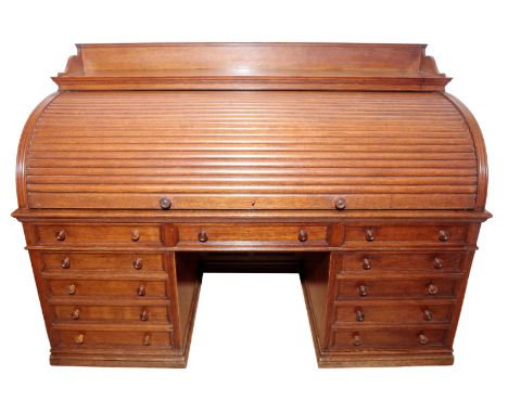 A VICTORIAN OAK ROLL TOP DESK BY HOWARD & SONS the upper section with a galleried top over a lifting tambour front opening to