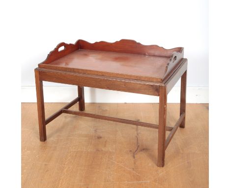 A MAHOGANY BUTLER'S TRAYthe shaped surround with twin pierced handles; together with a stand terminating on block legs, 51cm 