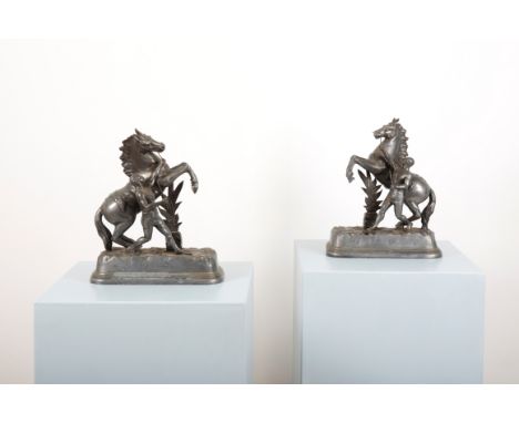 AFTER GUILLAUME COUSTOU: A PAIR OF SPELTER MODELS OF MARLY HORSES the grooms holding the reins of the rearing horses, on a na