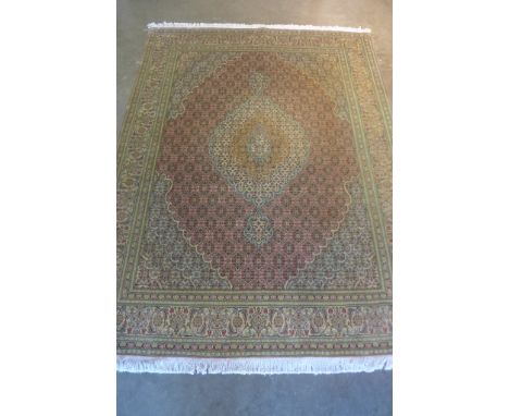 A fine Tabriz, hand knotted, woollen rug with pale red central field, approximately 198cm x 151cm, some light wear otherwise 
