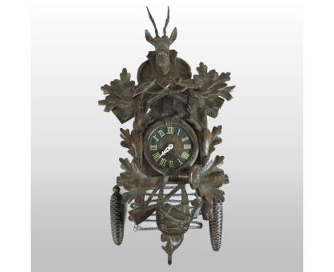A 19th century Black Forest style cuckoo clock, the dial showing Roman numerals, surrounded by carved oak leaves, a hunting h
