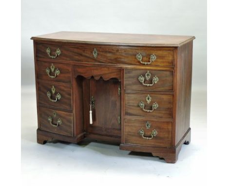 A George III mahogany bow front kneehole desk, containing an arrangement of seven drawers, about a central recessed cupboard,