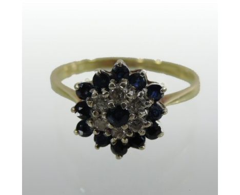 An 18 carat gold sapphire and diamond cluster ring, the central sapphire surrounded by a row of diamonds and a further row of