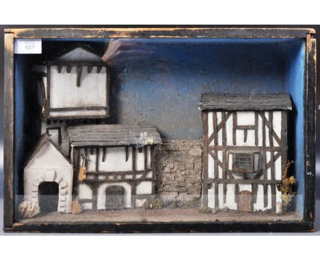 An early 20th Century glass cased model house / street scene depicting thatched buildings and stone wall. The diorama housed 