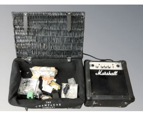 A Marshall MG10CF amplifier and a wicker hamper containing further musical equipment including guitar pickups, etc. 