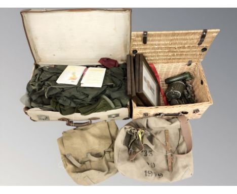 A wicker hamper and canvas luggage case containing militaria including frame prints, canteen, torch, morse code tapper, heads