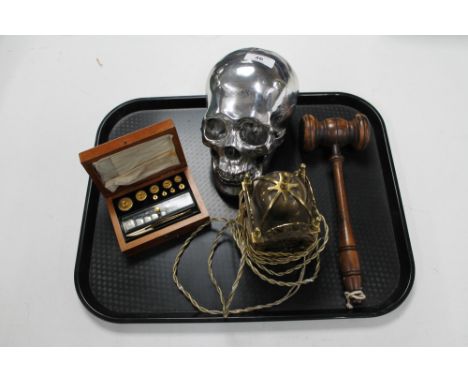 An auctioneer's wooden gavel, a cast alloy skull, a brass cased electric clock and a cased set of weights 