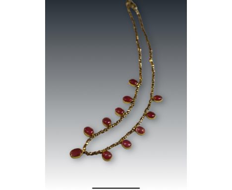 A Cabochon Ruby and Yellow Metal Fringe Necklace set to the front with eleven slightly graduated oval shaped cabochon rubies 