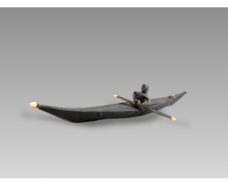 An Inuit Kayak Model. Artic Canada ca. Late 19th Century.A good kayak model and figurine made of seal hide complete with padd