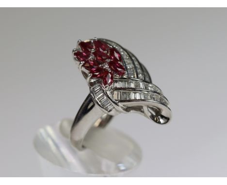 An unusual Ruby and Diamond Dress Ring,mounted in platinum set with nine pear shaped rubies within a calibre cut baguette dia