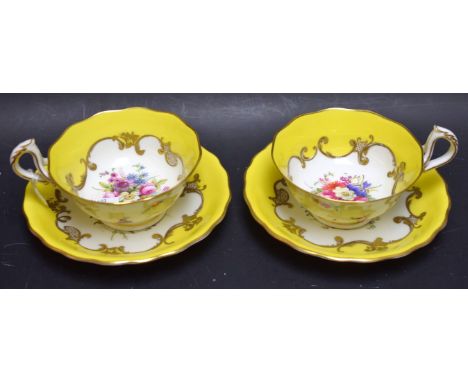 A pair of Royal Worcester teacups and saucers, painted by Phillips, signed, with summer flowers on a yellow ground, printed m