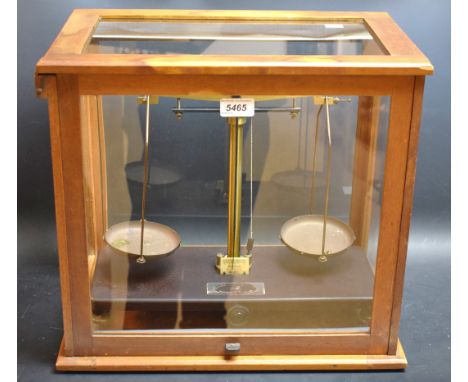 A set of brass balance scales in a clear glass case, 40cm high, 45cm wide
