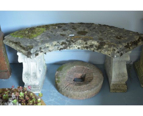 A stone composite garden bench on scrolling supports; together with a small circular plinth.