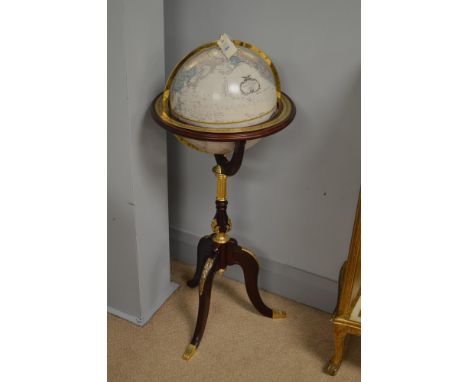 A 20th Century reproduction globe contained within a brass and mahogany surround above a central column and raised on a tripa