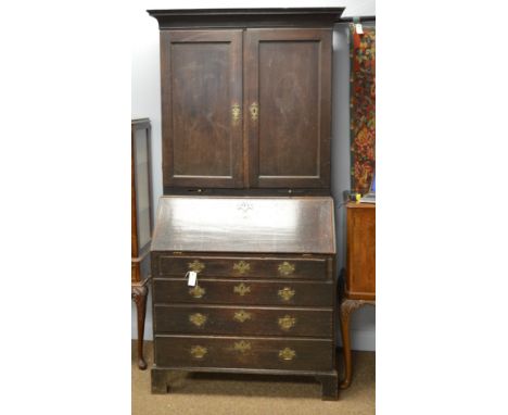 A George III oak bureau bookcase, the projecting cornice above a pair of panel doors and two candle slides on a bureau base w