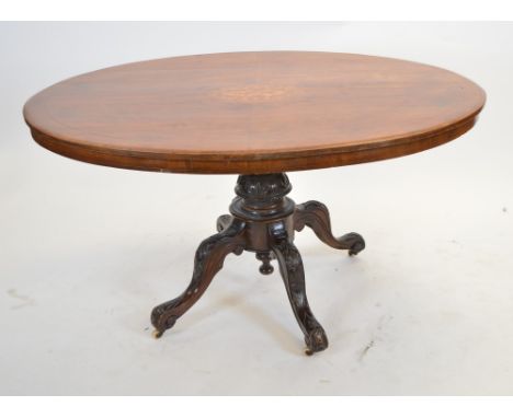 A Victorian walnut breakfast table, the oval top with a central inlaid medallion above a turned central column and acanthus c