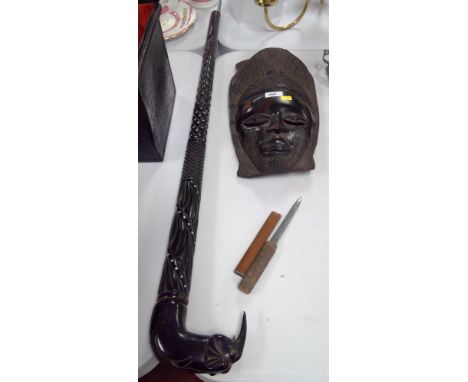 A black ebonised hardwood carved walking stick with elephant theme; together with a carved African mask; and a letter opener.