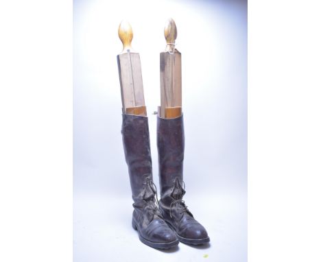 A pair of vintage leather riding boots with wooden boot stretchers.