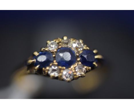 A sapphire and diamond ring, the three graduated facet-cut sapphires surrounded by six eight-cut diamonds, on 18ct. yellow go