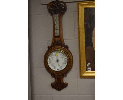 An aneroid barometer in carved and stained oak banjo pattern mount.