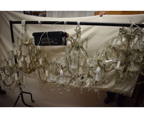 Three glass chandeliers with scrolling arms and lustre drops each holding approximately eighteen light fittings.