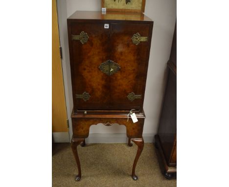 A figured walnut cabinet two figured walnut doors with inlaid hinge and lock plates opening to reveal interior with a single 