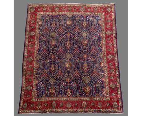 A PERSIAN STYLE CARPET with floral filled blue field and cerise border (general wear) 12' 6" (381 cms) x 9' 9" (297 cms)