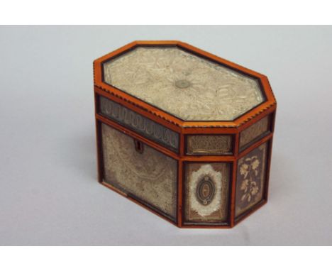 A ROLLED PAPER TEA CADDY of chamfered rectangular form, set with glazed panels of scroll work, some with pearl glass or ruby 