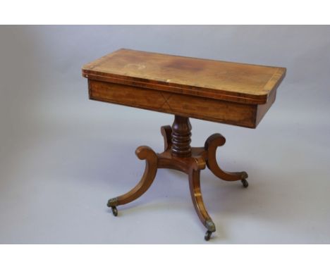 A REGENCY MAHOGANY CARD TABLE the revolving rounded rectangular top with rosewood cross banding on a turned column and down c