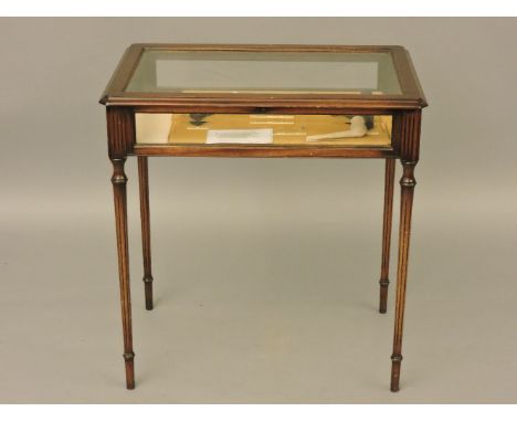 A reproduction mahogany table cabinet, on turned legs, containing a display with a pipe mould, two clay pipes, and a tool for