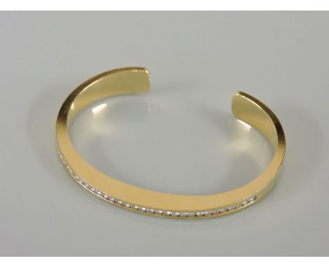 An 18ct gold diamond set torque bangle, with a row of channel set brilliant cut diamonds, believed to weigh approximately 1.0
