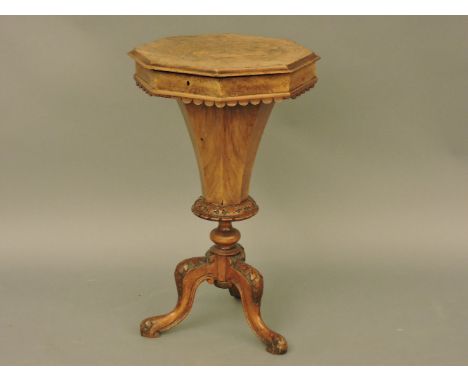 A Victorian walnut octagonal work table, inlaid top opening to reveal fitted interior over fluted wool box, and standing on t