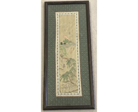 A framed and glazed Oriental embroidered silk panel depicting a rural lake and mountain scene.  Frame sixe approx. 63 x 26.5c
