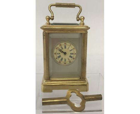 A miniature brass carriage clock with hand painted ceramic panels and bevel edged glass. Blue ceramic panels depicting cherub