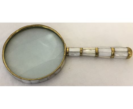 A magnifying glass with mother of pearl panelled detail to handle and glass surround.  Glass approx. 10cm diameter.