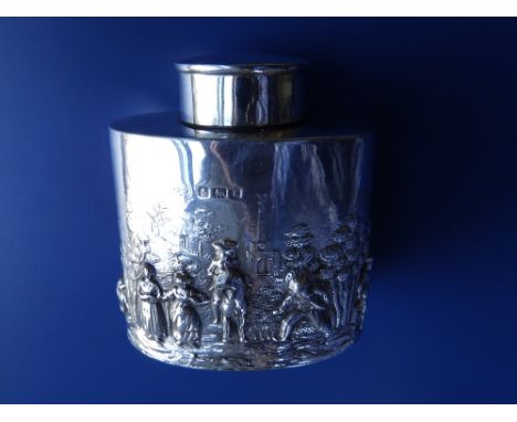An Edwardian oval silver tea caddy modelled in relief with a scene showing a gentleman on horseback in the company of rustic 