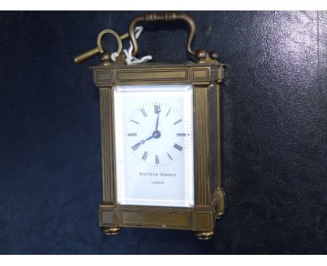 A Swiss brass carriage clock with white enamel dial retailed by Matthew Norman of London, 5" high excluding handle.