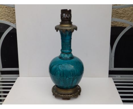 A gilt metal mounted turquoise glazed art pottery table lamp, of bottle shape decorated with cranes and bulrushes, the metal 