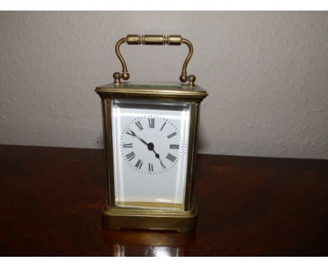 A brass carriage clock with white enamel dial, 4.5" excluding handle.