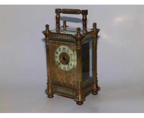 A French ornate brass carriage clock, having an openwork gilt metal surround to the circular enamel dial including a pair of 