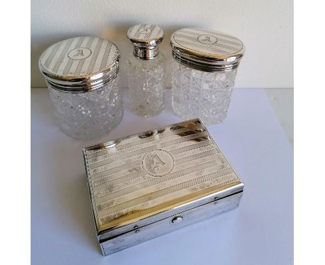 A George V silver ladies vanity set comprising oblong box with fitted interior and three silver topped bottles (tallest 9 cm)