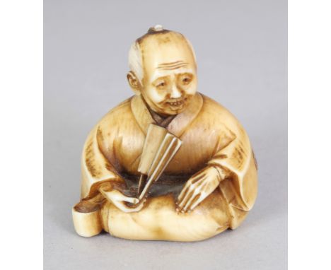 A GOOD QUALITY JAPANESE MEIJI PERIOD STAINED IVORY NETSUKE OF A SEATED MAN, holding a fan, his robes inlaid with small engrav