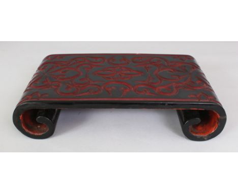 A CHINESE RECTANGULAR TIXI LACQUER SCROLL END STAND, with a layered red formal scroll design reserved on a black ground, the 