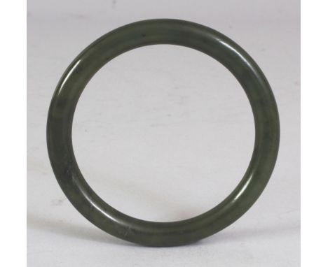 A CHINESE SPINACH GREEN JADE BANGLE, 3in diameter, the inner rim 2.25in diameter.
