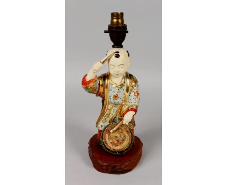 AN EARLY/MID 20TH CENTURY JAPANESE SATSUMA STYLE CERAMIC FIGURE OF A BOY DRUMMER, fitted for electricity on a carved wood sta