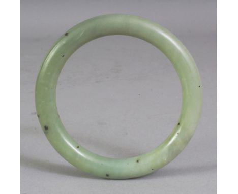 A CHINESE CELADON GREEN JADE BANGLE, 3.1in diameter, the inner rim 2.25in diameter.