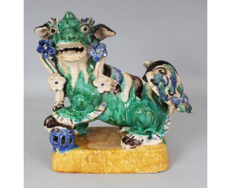 A 20TH CENTURY CHINESE SHIWAN GLAZED CERAMIC MODEL OF A BUDDHISTIC LION, standing on rounded yellow glazed rectangular plinth