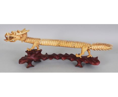 AN EARLY 20TH CENTURY JAPANESE ARTICULATED BONE MODEL OF A DRAGON, together with a fitted wood stand, 5.5in high overall on s
