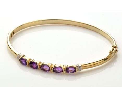 A 9ct. yellow gold, amethyst and diamond bangle, the five oval facet cut amethysts flanked by three diamonds to each side, on