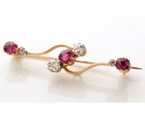 An Edwardian ruby and diamond bar brooch, set with three circular facet cut rubies and four old cut diamonds on a shaped bar,